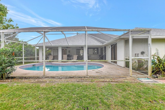 view of swimming pool featuring a lanai, ceiling fan, a lawn, and a patio