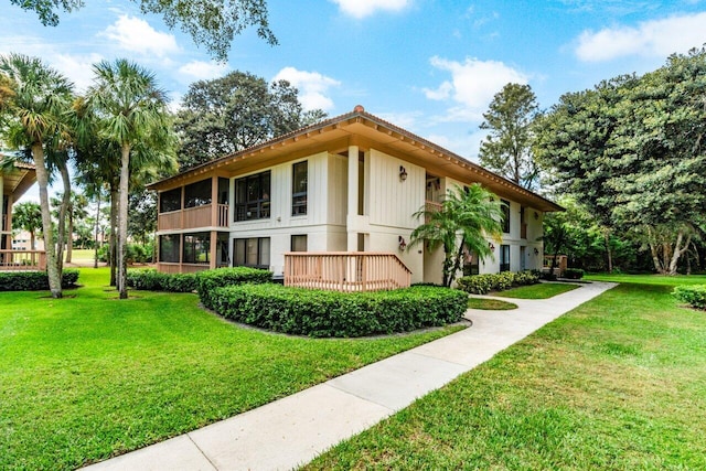 rear view of property featuring a lawn and a wooden deck