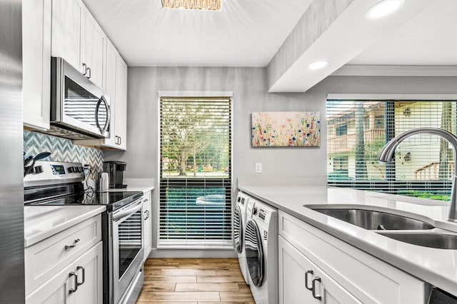 kitchen with white cabinets, appliances with stainless steel finishes, light wood-type flooring, and sink