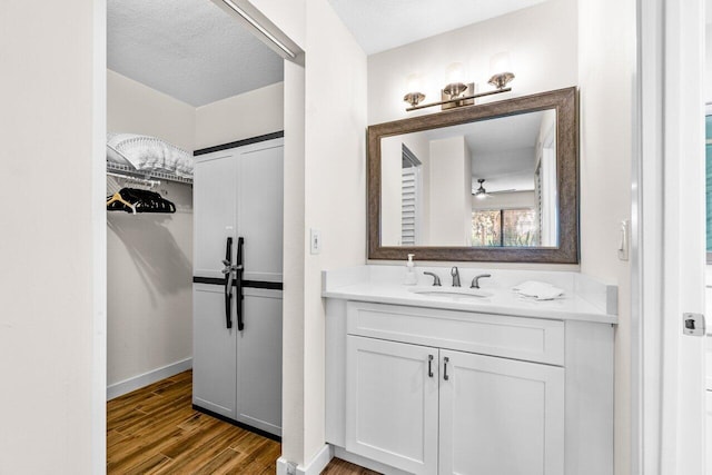 bathroom featuring vanity, ceiling fan, wood-type flooring, and a textured ceiling