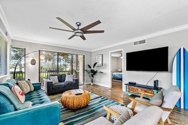 living room featuring wood-type flooring, a textured ceiling, ceiling fan, and ornamental molding