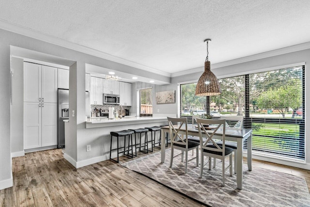 dining space with crown molding, light hardwood / wood-style floors, and a textured ceiling