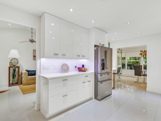 kitchen with high end refrigerator, light tile patterned floors, tasteful backsplash, and white cabinetry