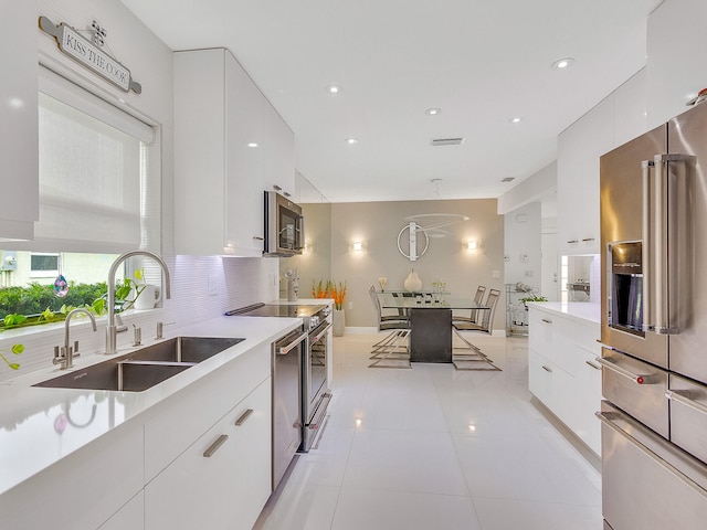 kitchen featuring white cabinets, appliances with stainless steel finishes, hanging light fixtures, and sink