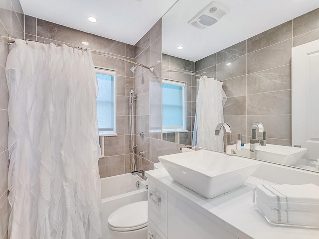 full bathroom with vanity, shower / bath combination with curtain, tile walls, and toilet