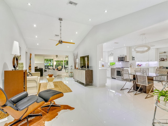 tiled living room with ceiling fan and high vaulted ceiling