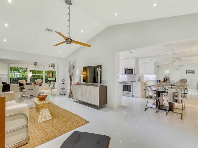 tiled living room with ceiling fan and high vaulted ceiling