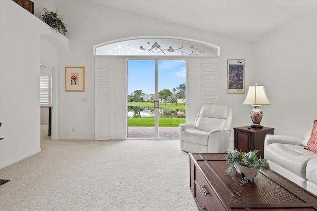 living room with plenty of natural light, a water view, light colored carpet, and vaulted ceiling