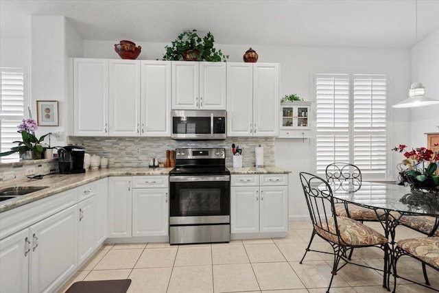 kitchen featuring white cabinetry, light tile patterned floors, decorative light fixtures, and appliances with stainless steel finishes