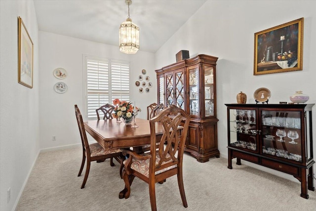 carpeted dining space featuring a notable chandelier and lofted ceiling