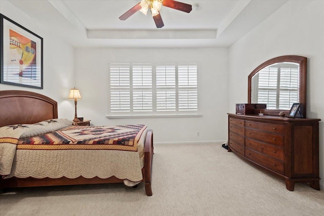 carpeted bedroom with ceiling fan and a raised ceiling