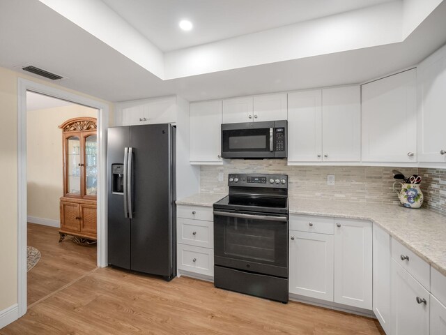 kitchen featuring appliances with stainless steel finishes, backsplash, light hardwood / wood-style flooring, and white cabinetry