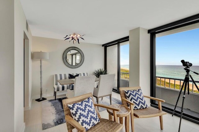 sitting room with a water view, light hardwood / wood-style floors, and a beach view