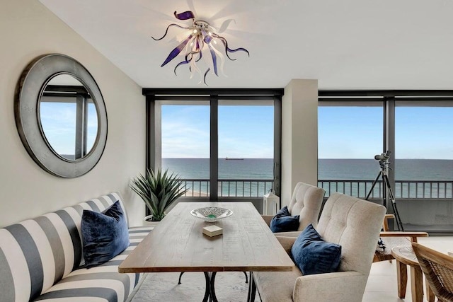 living room featuring floor to ceiling windows, a water view, and a chandelier