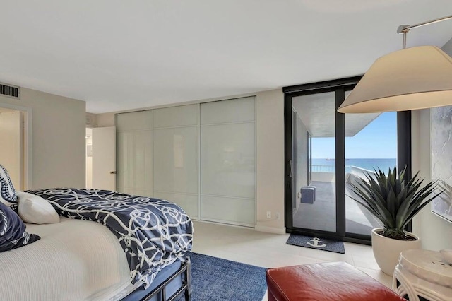 bedroom with floor to ceiling windows, a water view, access to outside, and a closet