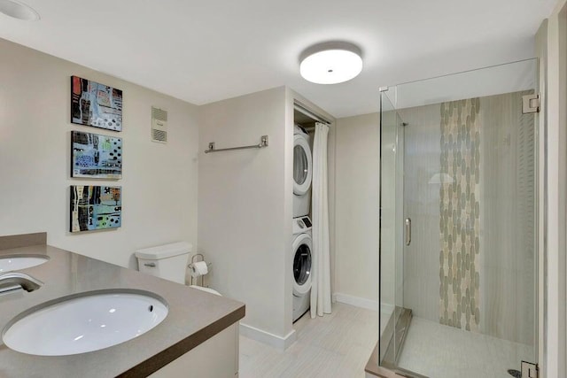 bathroom featuring tile patterned flooring, vanity, a shower with door, and stacked washer / dryer