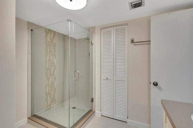 bathroom featuring vanity, a shower with shower door, and wood-type flooring