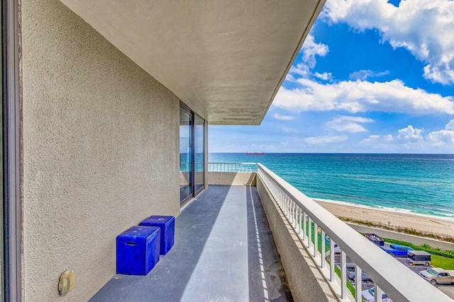 balcony with a water view and a view of the beach