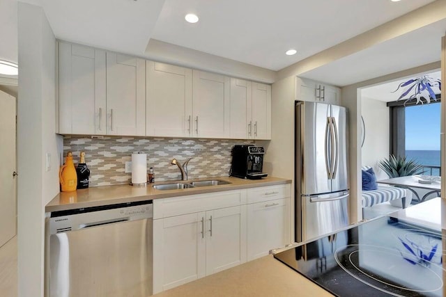 kitchen featuring appliances with stainless steel finishes, tasteful backsplash, white cabinetry, and sink