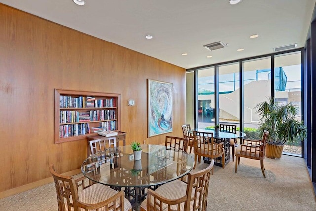 dining space with wood walls and light colored carpet