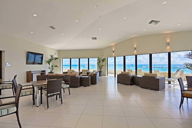 interior space with light tile patterned floors, a water view, and high vaulted ceiling