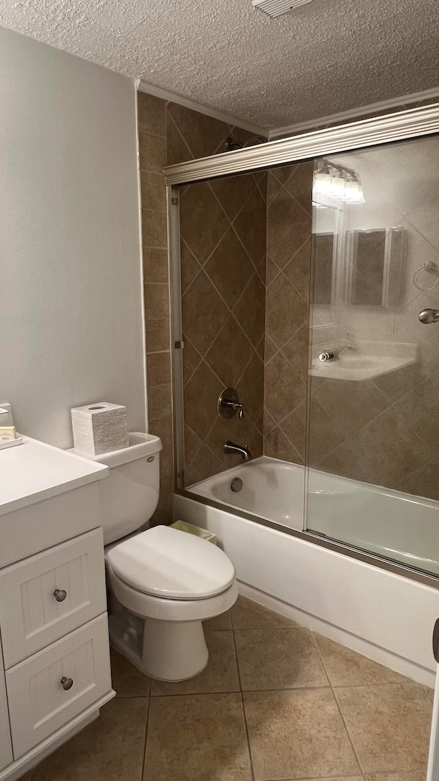 full bathroom featuring tile patterned floors, bath / shower combo with glass door, a textured ceiling, toilet, and vanity