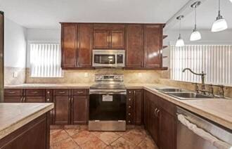 kitchen with pendant lighting, sink, decorative backsplash, light tile patterned floors, and appliances with stainless steel finishes