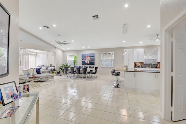 tiled living room with ceiling fan and vaulted ceiling