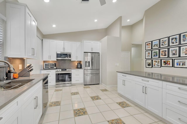 kitchen with lofted ceiling, white cabinets, sink, tasteful backsplash, and stainless steel appliances