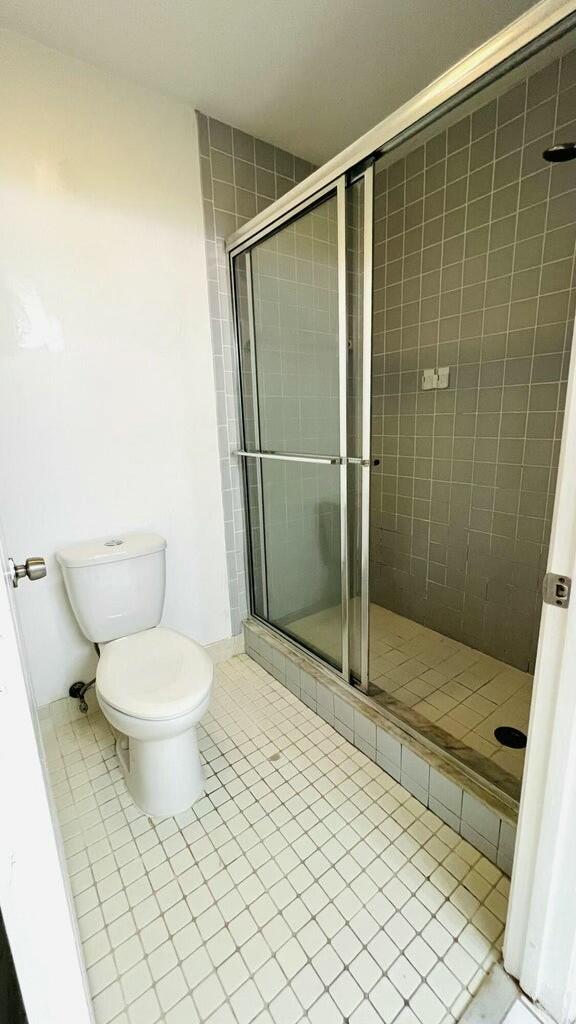 bathroom featuring toilet, tile patterned floors, and a shower with shower door