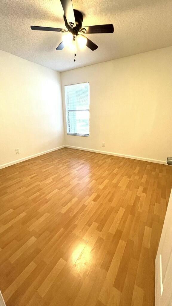 spare room featuring ceiling fan, light hardwood / wood-style floors, and a textured ceiling