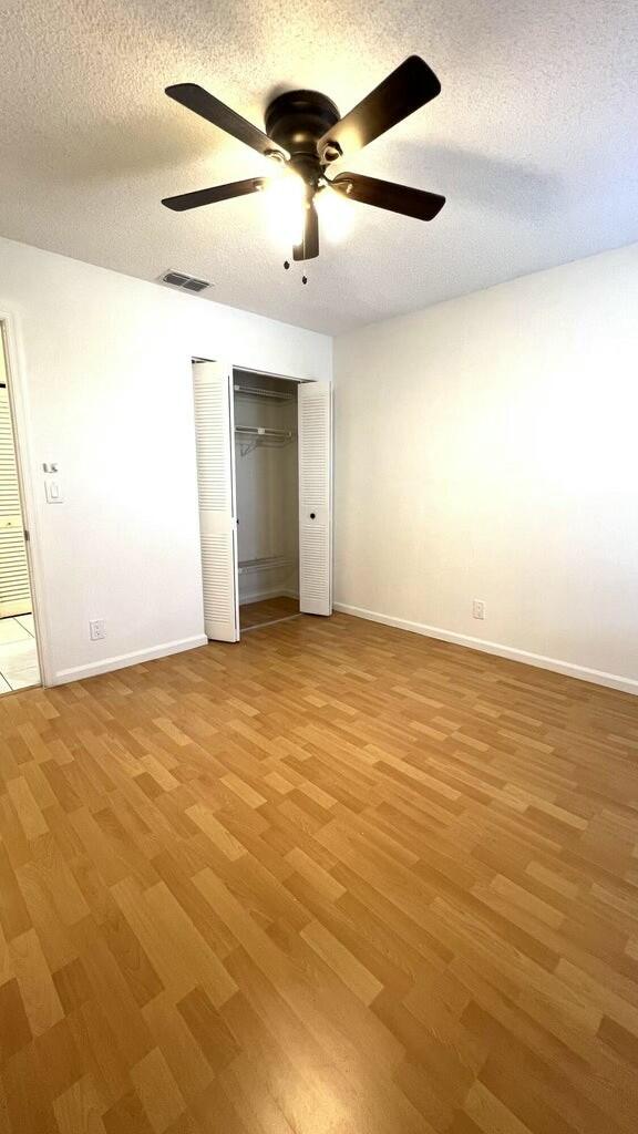 unfurnished bedroom featuring ceiling fan, a textured ceiling, and light hardwood / wood-style flooring