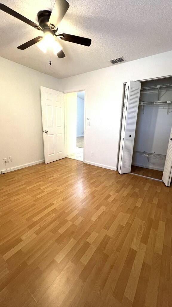 unfurnished bedroom featuring ceiling fan, a textured ceiling, and hardwood / wood-style flooring