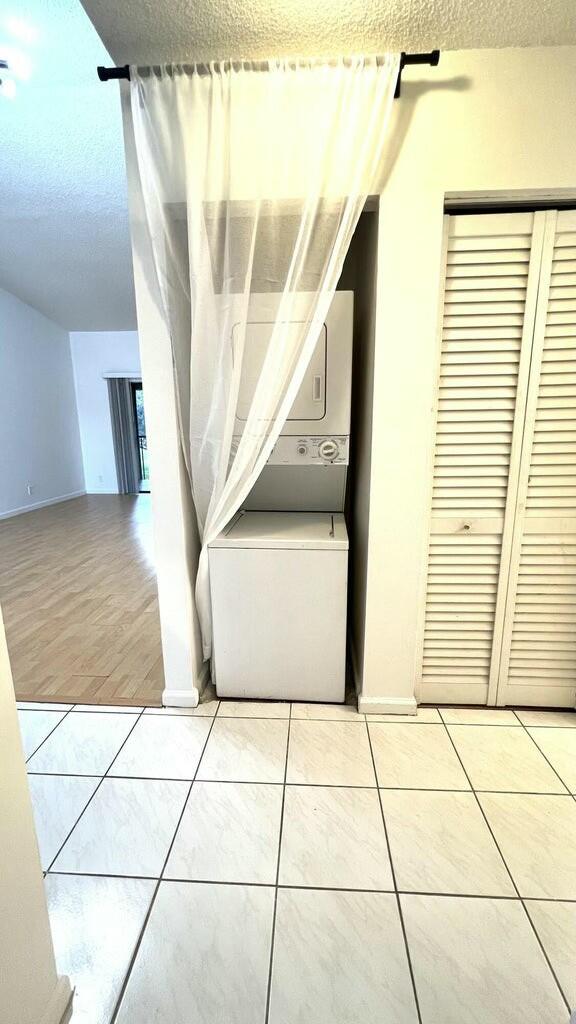 hallway with hardwood / wood-style floors, stacked washing maching and dryer, and a textured ceiling