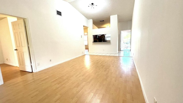 interior space featuring vaulted ceiling, a textured ceiling, and light hardwood / wood-style flooring