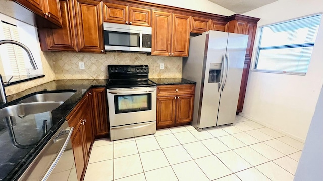 kitchen featuring decorative backsplash, dark stone counters, stainless steel appliances, vaulted ceiling, and light tile patterned flooring