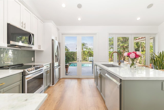 kitchen featuring appliances with stainless steel finishes, a wealth of natural light, french doors, and an island with sink