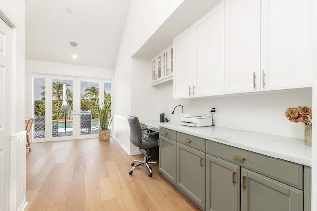 office space with french doors, built in desk, vaulted ceiling, and light hardwood / wood-style flooring