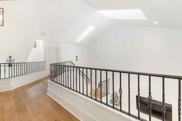 hallway with light hardwood / wood-style floors and lofted ceiling with skylight