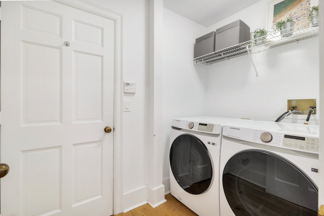 clothes washing area with separate washer and dryer and light hardwood / wood-style flooring