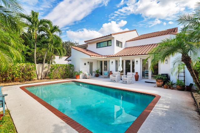 rear view of house featuring a patio area and a fenced in pool