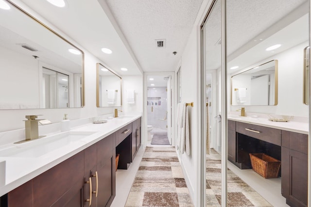 bathroom featuring vanity, tile patterned floors, a textured ceiling, and toilet