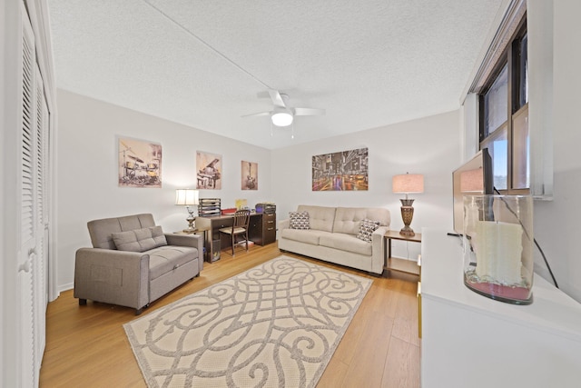 living room with ceiling fan, a textured ceiling, and hardwood / wood-style flooring