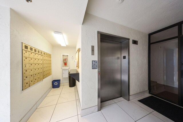 hall featuring light tile patterned floors, mail boxes, and elevator