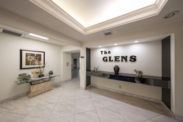 corridor with a tray ceiling, crown molding, and a textured ceiling