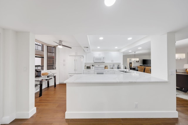 kitchen featuring sink, kitchen peninsula, light hardwood / wood-style floors, white appliances, and white cabinets