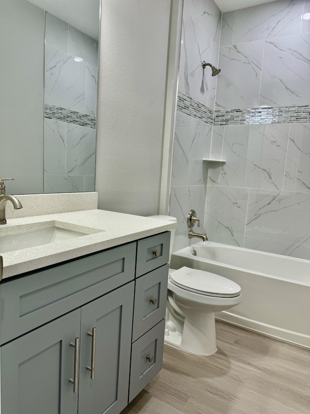 full bathroom featuring hardwood / wood-style floors, tiled shower / bath combo, toilet, and vanity