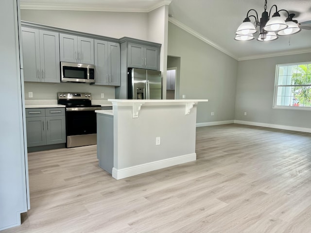 kitchen featuring a breakfast bar, gray cabinets, crown molding, and stainless steel appliances