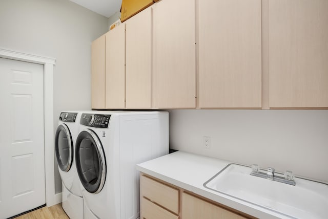 laundry area featuring cabinets, independent washer and dryer, sink, and light hardwood / wood-style flooring