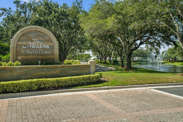 community / neighborhood sign with a yard and a water view